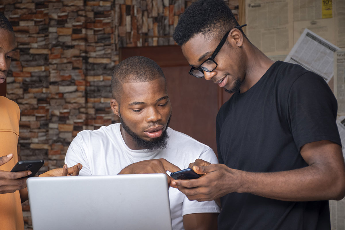 young african men discussing project while using their laptop phones